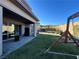 Spacious backyard with a grass lawn, covered patio, and playset at 12422 Tudor Arch Dr, Las Vegas, NV 89138