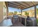 Outdoor kitchen with grill, fridge, and pizza oven under pergola at 9820 Maiden Pink Ave, Las Vegas, NV 89149