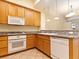 Well-lit kitchen with white appliances, wood cabinets, granite countertops, and tile flooring at 38 E Serene Ave # 134, Las Vegas, NV 89123