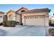 Tan house with brown roof, two-car garage, and landscaping at 22 Arborfield Ct, Henderson, NV 89012