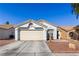 Front view of a single-story house with a beige exterior and a two-car garage at 3327 Outlook Point St, North Las Vegas, NV 89032