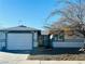 Single story home with a white garage door and landscaping at 4981 Alondra Dr, Las Vegas, NV 89118