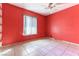 Simple bedroom with red walls, tiled floors, and a ceiling fan at 57 Marion Dr, Las Vegas, NV 89110