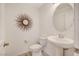 Small bathroom with white pedestal sink, toilet, and a round mirror at 8749 Black Cordon Rd, Las Vegas, NV 89139