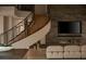 Living room with a curved staircase, fireplace, and large TV at 8913 Canyon Springs Dr, Las Vegas, NV 89117