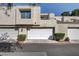 Tan stucco exterior of townhome with white garage doors and landscaping at 8945 Clairton Ct, Las Vegas, NV 89117