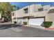 Tan stucco exterior of townhome with white garage doors and landscaping at 8945 Clairton Ct, Las Vegas, NV 89117