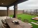 Backyard patio featuring turf grass, brick retaining walls, dark metal fence and outdoor dining area at 12381 Foxtail Run Ave, Las Vegas, NV 89138