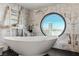 Bathroom with a large soaking tub, marble walls, and a circular window with a view at 2857 Paradise Rd # 2203, Las Vegas, NV 89109