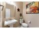 Simple and elegant bathroom with white pedestal sink and large art at 3158 Biancavilla Ave, Henderson, NV 89044