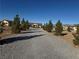 Gravel driveway lined with trees leads to a charming yellow house at 3720 W Charleston Park Ave, Pahrump, NV 89048