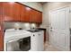 Well-lit laundry room with modern washer and dryer, wooden cabinets, and convenient utility sink at 8199 Pinnacle Peak Ave, Las Vegas, NV 89113