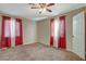 Spacious carpeted bedroom with a ceiling fan and windows dressed with red and white curtains at 132 Continental Ave, Henderson, NV 89015