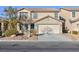 Two-story house with a beige exterior, teal door, and attached garage at 312 Bella Calabria Ave, Las Vegas, NV 89183