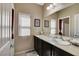 Bathroom featuring dual sinks, dark cabinets, and large mirror and bright natural lighting at 9417 Sand Tiger Ave, Las Vegas, NV 89148