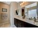 Bathroom featuring dual sinks, dark cabinets, a large mirror, and decorative chandelier-style light at 9417 Sand Tiger Ave, Las Vegas, NV 89148