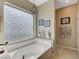 Bathroom featuring a tub, a textured glass window and a chandelier-style light at 9417 Sand Tiger Ave, Las Vegas, NV 89148