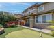 Beautiful backyard with covered patio, putting green, and view of the two-story home's exterior at 10273 Aragon Crown Rd, Las Vegas, NV 89135