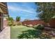 A well-maintained backyard with a putting green, stone retaining wall, and mature trees at 10273 Aragon Crown Rd, Las Vegas, NV 89135