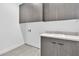 Modern laundry room featuring gray cabinets, a white countertop, and essential laundry connections at 10739 Agate Cliffs Ave, Las Vegas, NV 89135