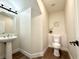 Clean bathroom with pedestal sink, toilet and wood-look floors at 109 Lakewood Garden Dr, Las Vegas, NV 89148