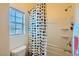 Clean bathroom with a shower featuring a colorful shower curtain, a toilet, and a window with blinds at 1738 Sonoran Bluff Ave, Henderson, NV 89014