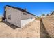 View of the home's exterior, with stucco and a brown trim, set against a spacious, walled-in dirt backyard at 3875 Sebasco Dr, Las Vegas, NV 89147