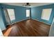 Bedroom with light blue walls, wood-look floors, and multiple windows at 529 Beckton Park Ave, Las Vegas, NV 89178