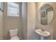 Small bathroom with pedestal sink, toilet, and round mirror at 6217 Red Jamboree Ct, Las Vegas, NV 89130