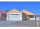 Tan one-story house with a two-car garage and landscaped yard at 8836 Big Bear Pines Ave, Las Vegas, NV 89143