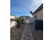 A backyard pathway bordered by rocks and palm trees, leading to a gate, adjacent to an HVAC unit at 2540 E Sparrow Way, Pahrump, NV 89048