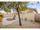 This backyard features desert landscaping, a covered patio, and mature trees at 5804 Sassa St, Las Vegas, NV 89130