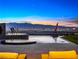 Stunning infinity pool with a fire feature and views of the Las Vegas skyline at dusk at 591 Overlook Rim Dr, Henderson, NV 89012