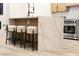 Kitchen island with marble countertop, light wood cabinets, and black metal stools at 10369 Niagara Falls Ln, Las Vegas, NV 89144