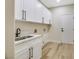 Bright laundry room with white cabinets, quartz countertops, and vinyl flooring at 10369 Niagara Falls Ln, Las Vegas, NV 89144