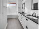 Bathroom with double vanity, black countertop, and white cabinets at 7627 Alexander Hills St, Las Vegas, NV 89139