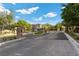 Gated community entrance with lush landscaping and mature trees on a sunny day at 9625 Ponderosa Skye Ct, Las Vegas, NV 89166