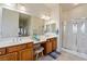 Bright bathroom featuring double sinks, vanity seating, and a glass-enclosed shower at 5130 Agio Ave, Pahrump, NV 89061
