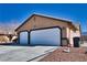 Two-car garage with white doors and desert landscaping at 5001 Ray Frank Blvd, Pahrump, NV 89060