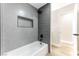 Updated bathroom featuring gray hexagon tile, a shower, and a white bathtub at 5153 Woodruff Pl, Las Vegas, NV 89120