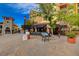 Charming street scene with outdoor seating, lush planters, and a directory board under a partly cloudy sky at 6 Lilla Rosa St, Henderson, NV 89011