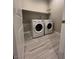 Functional laundry room with modern washer and dryer units, tiled flooring, and a convenient storage shelf at 6 Lilla Rosa St, Henderson, NV 89011