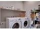 Bright laundry room with a front loading washer and dryer, as well as storage shelving for supplies at 6 Lilla Rosa St, Henderson, NV 89011