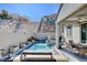 Inviting backyard with a sparkling pool, outdoor dining set, lush artificial turf, and scenic mountain views at 6 Lilla Rosa St, Henderson, NV 89011