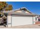 View of a two-car garage with attached house and small yard at 6200 Budnick Cir, Las Vegas, NV 89130