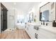 This bright bathroom has dual sinks, a soaking tub, and a walk-in shower with black hardware and wood-look flooring at 6304 Tanzanite Ave, Las Vegas, NV 89130