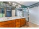 Bathroom featuring double sink vanity, large mirror, and a shower-tub combo with glass doors at 6712 Painted Canyon Ct, Las Vegas, NV 89130