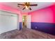 Bright bedroom featuring a ceiling fan, closet, and pink and purple accent walls at 6712 Painted Canyon Ct, Las Vegas, NV 89130