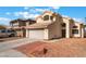 View of two-story home with beige exterior, two-car garage, and desert landscaping at 6712 Painted Canyon Ct, Las Vegas, NV 89130