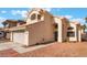 View of two-story home with beige exterior, two-car garage, and desert landscaping at 6712 Painted Canyon Ct, Las Vegas, NV 89130